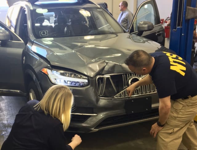 NTSB officials inspect Uber’s Volvo XC-90, damaged from where it struck a pedestrian in a fatal accident. (Image courtesy of the AP.)