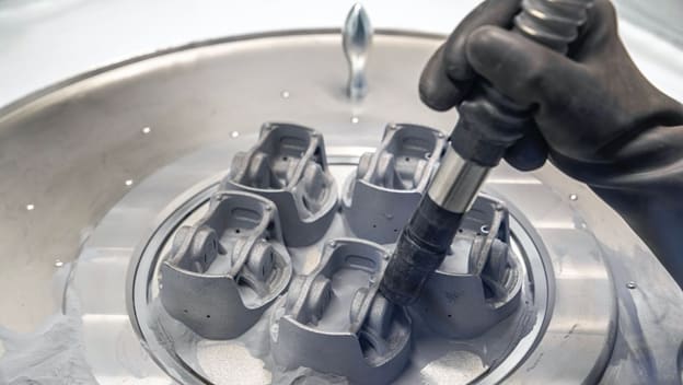 Excess powder is removed from printed pistons at Porsche. The organic design follows the natural path of stress through the part. (Image courtesy of Porsche.)